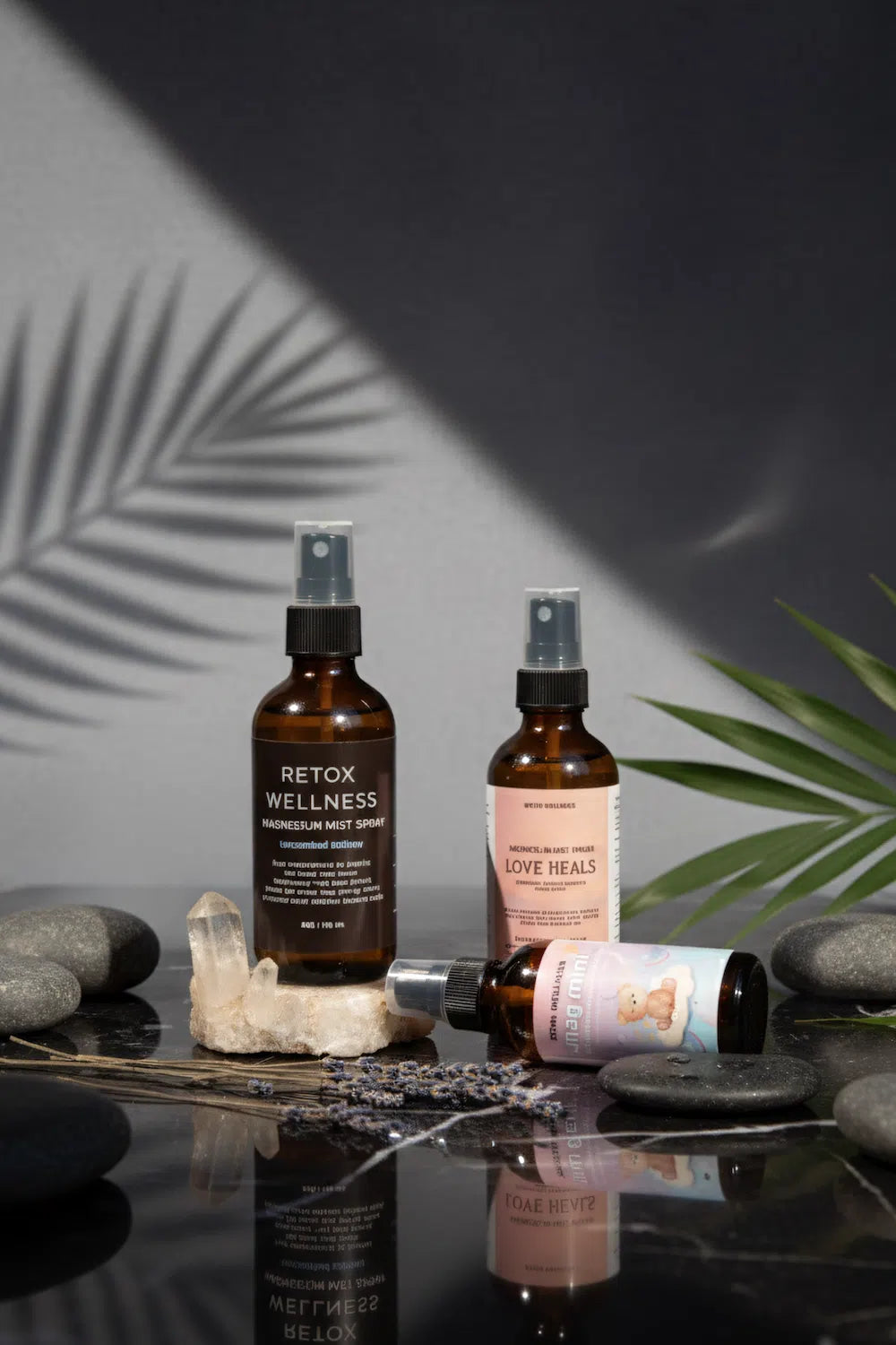 Three wellness spray bottles arranged on a glossy black surface with stones, dried lavender